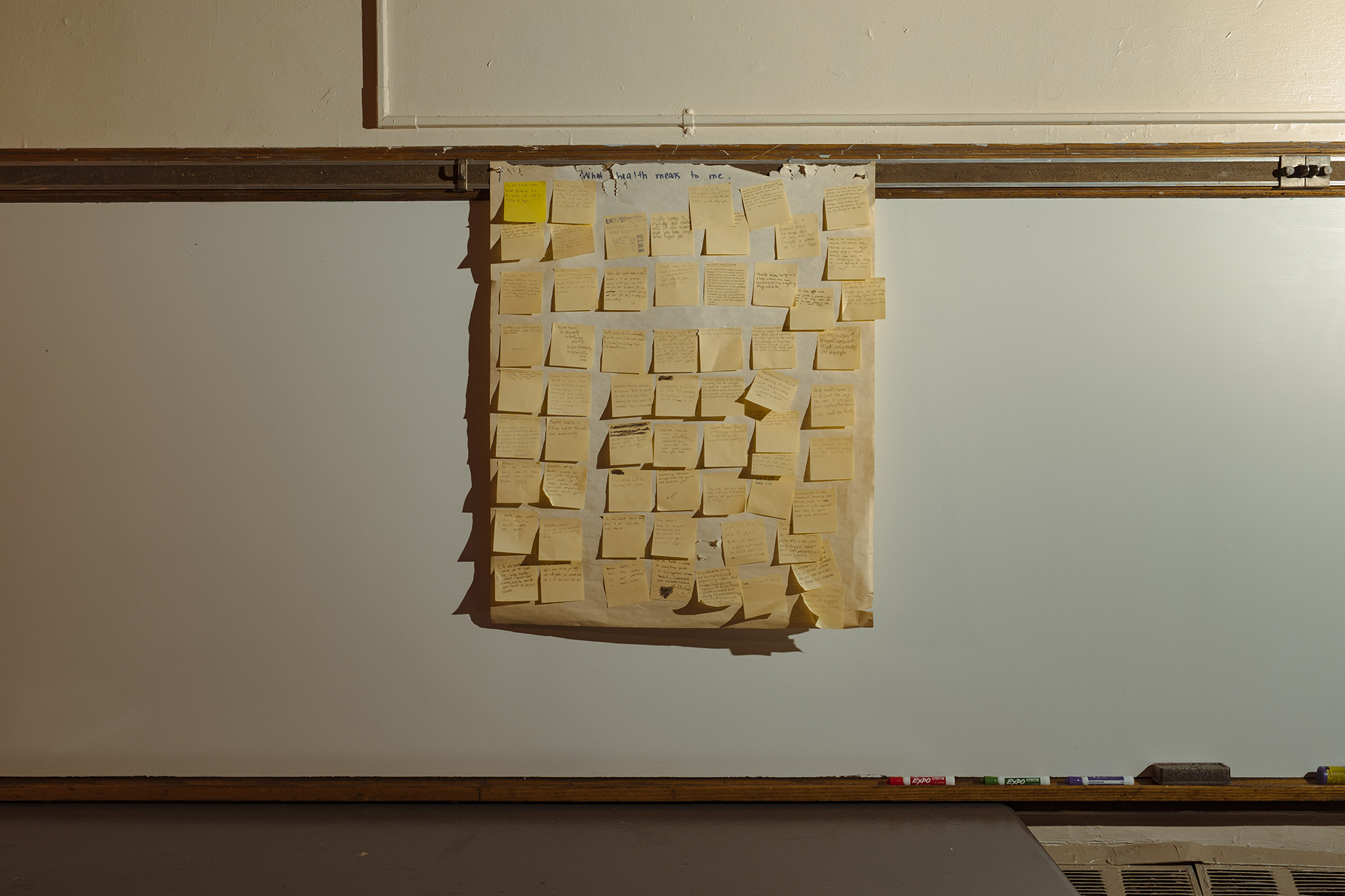 Large grid of Post-It Notes hanging in a classroom. 