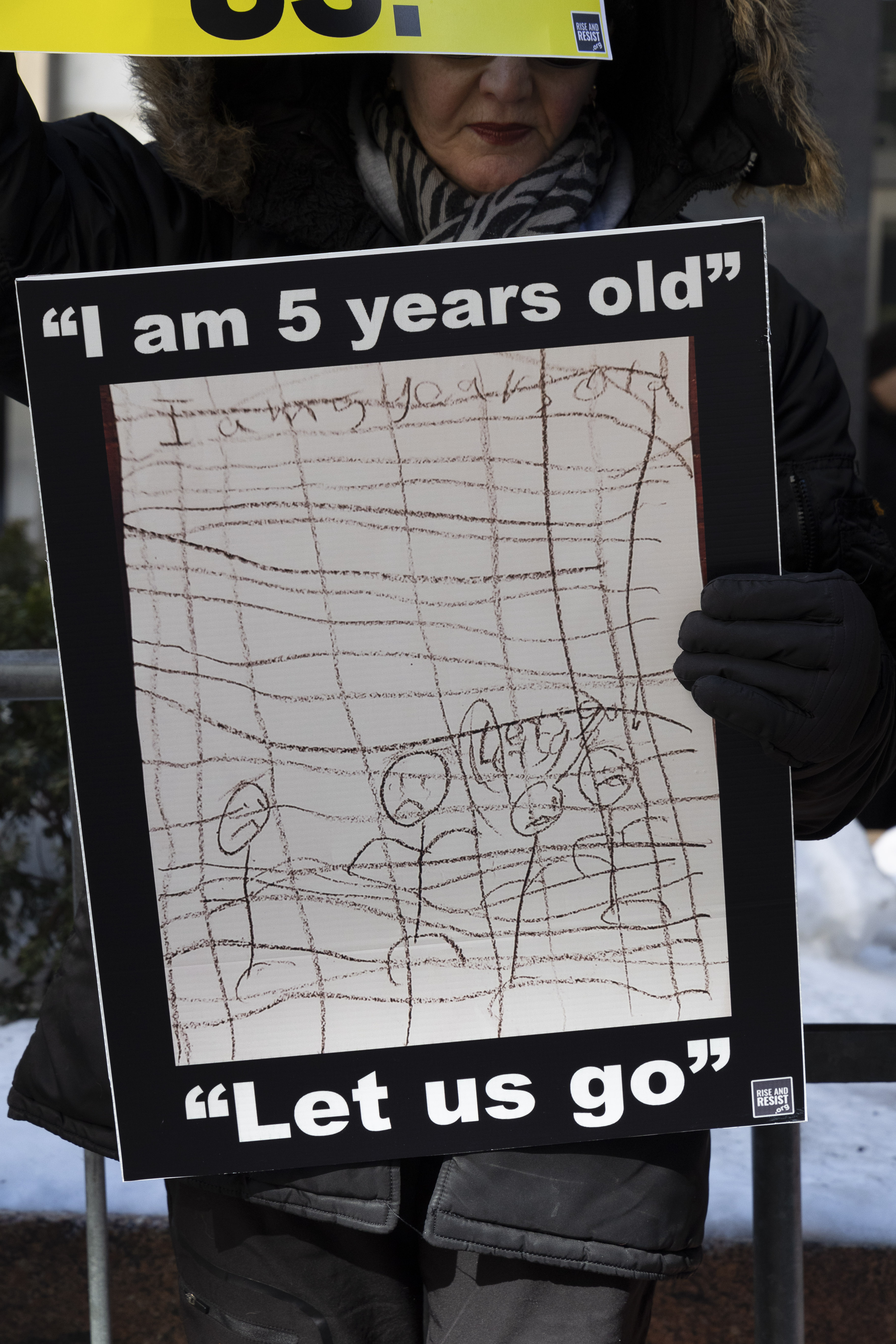 A protester holds a sign that reads "I am 5 years old. Let us go."